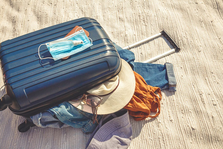 A packed suitcase for a quick getaway or staycation with mask and sanitiser &copy;Shyntartanya/Shutterstock.com