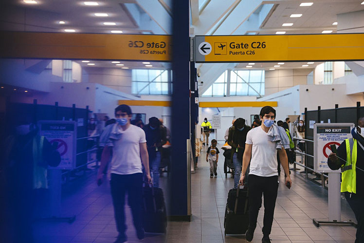 Travelers wearing protective masks walk through LaGuardia Airport (LGA) in New York, US on Christmas Eve &copy; Bloomberg via Getty Images